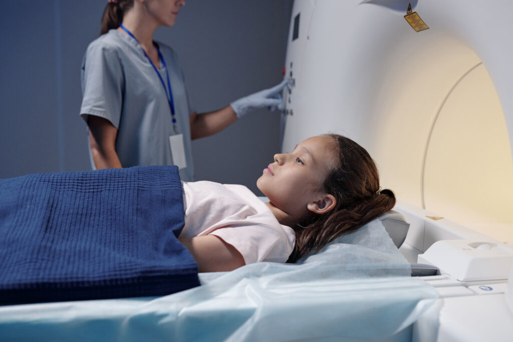 Criança realizando exame de imagem na radiologia pediátrica com acompanhamento profissional.